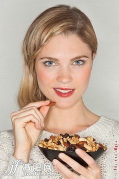 人,飲食,休閑裝,生活方式,影棚拍攝_557133567_Portrait of a beautiful woman eating dried fruit_創(chuàng)意圖片_Getty Images China