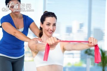 40到44歲,白人,30歲到34歲,室內(nèi),白晝_gic12763359_Brunette stretching with her coach and pink cloth in exercise room_創(chuàng)意圖片_Getty Images China